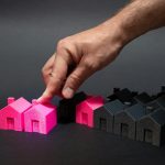 A hand is pointing at a small pink house