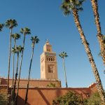 beige concrete building near palm trees under blue sky during daytime