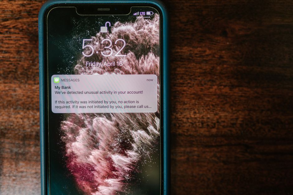Smartphone affichant une notification de banque en ligne posé sur une table en bois