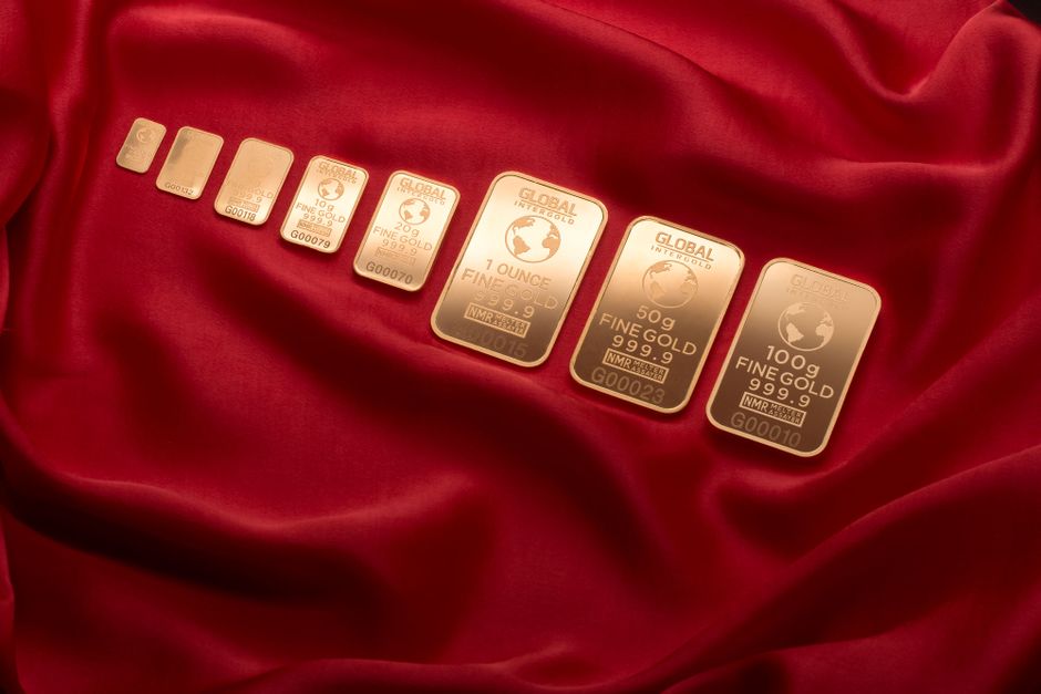 Gamme de lingotins d'or de différents poids alignés sur un tissu rouge